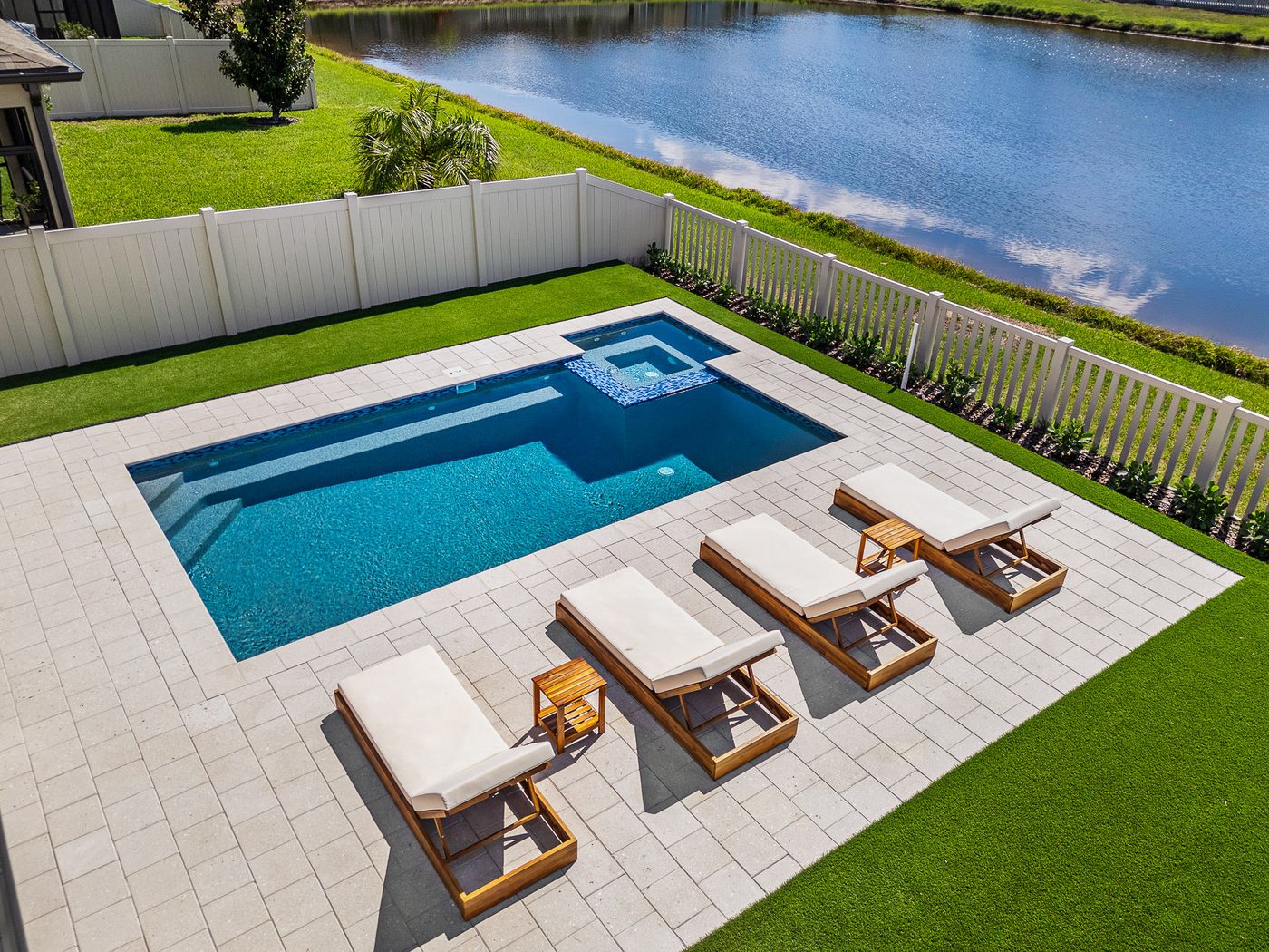 Aerial view of a Pool Perfection rectangular pool and spa overlooking a lake with lounge seating